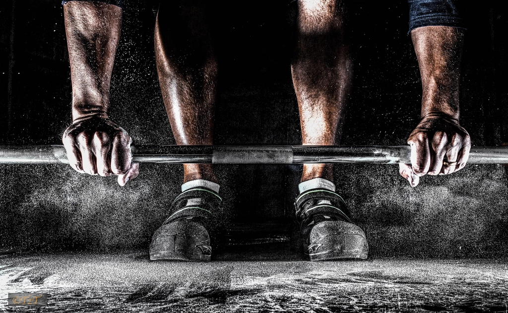 Hands gripping a chalked barbell
